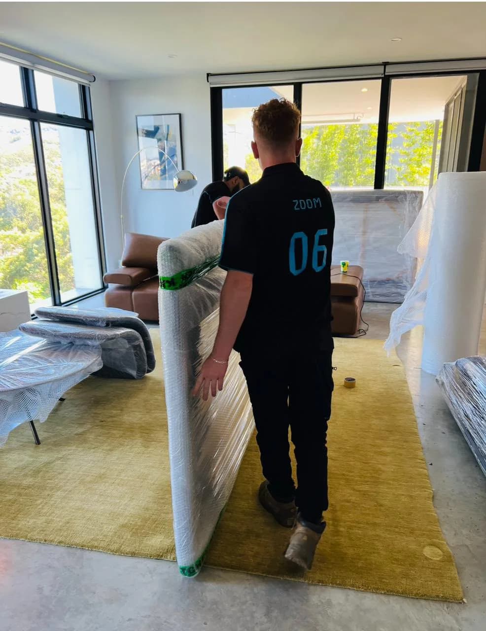 Removalists moving protected furniture through a modern home